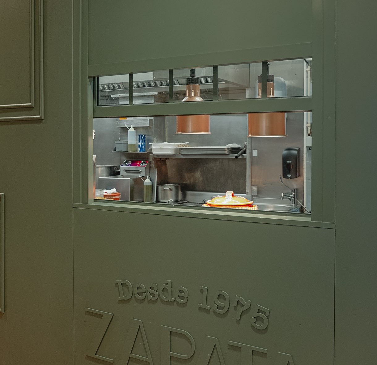 Passe-plat de la cuisine dans le mur vert au logo Zapata